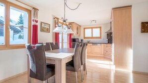 A modern kitchen with wooden cabinets, a dining table with chairs, and a chandelier.