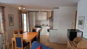 Een kleine woonruimte met een eethoek, een kitchenette en een slaapbank.