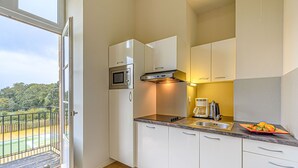 A modern kitchen with white cabinets, a built-in microwave, and a coffee maker. - Château De Kergonano by Interhome (Baden)