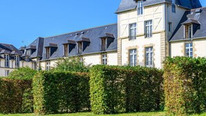 A row of traditional European-style buildings with steeply pitched roofs and dormer windows, surrounded by well-maintained hedges. - Château De Kergonano by Interhome (Baden)