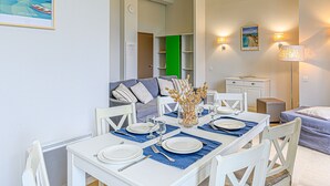 A dining area with a white table set for four, a blue sofa, and a green door in the background. - Château De Kergonano by Interhome (Baden)