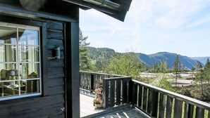 Una terraza de madera con vistas a montañas y árboles.