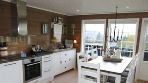 Una cocina moderna con armarios blancos, horno empotrado y comedor con sillas y mesa blancos.