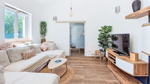 Ein modernes Wohnzimmer mit Sofa, Fernseher und Pflanzen.