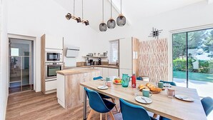 Eine moderne Küche mit Kochinsel, Holzboden und Essbereich mit blauen Stühlen und einem Holztisch.