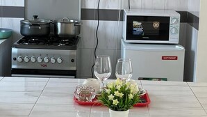 A kitchen with a stove, pots, a microwave, and a red tray with flowers and glasses. - Lux Suites Lantana Apartments westlands  (Nairobi)