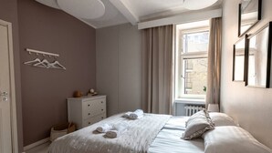 A bedroom with a bed, a dresser, a window with curtains, and a coat rack. - 2ndhomes Bright & Spacious 5BR Apartment (Helsinki)