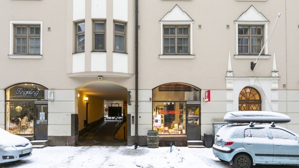 A building with multiple storefronts, including a jewelry store and a pharmacy, with a staircase leading to an upper entrance. - 2ndhomes Bright & Spacious 5BR Apartment (Helsinki)
