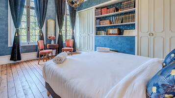A bedroom with a large bed, a bookshelf, a chair, and a window with curtains.