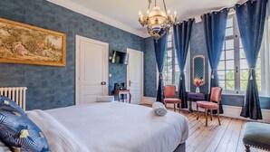 A bedroom with a large bed, a chandelier, a desk, two chairs, and a window with curtains. - Le manoir de la belle epoque (Béthencourt-sur-Mer)