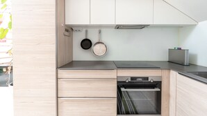 A modern kitchen with wooden cabinets, a built-in oven, and hanging pots. - 2ndhomes 2BR Penthouse w Terrace&Sauna (Helsinki)