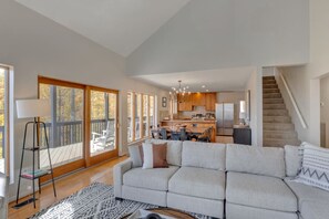 A spacious living area with a large sofa, a dining table, and a kitchen in the background.
