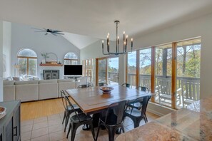 Relax in a spacious living area with a high ceiling, dining table, comfortable sofa, and flat-screen TV.