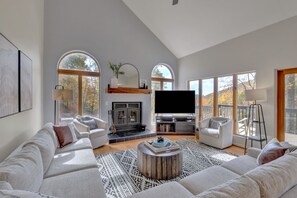 A spacious living room with a fireplace, large windows, and a flat-screen TV. - Spacious, private, four-season mountainside home close to Wintergreen and hiking (Roseland)