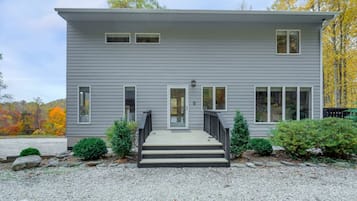 A two-story house with a front porch, a small front yard, and a gravel driveway.