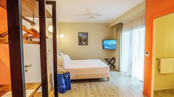 A hotel room with a bed, a television, a ceiling fan, and a window with curtains.