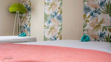 Relax in a serene space with a comfortable bed, tropical wallpaper, and a cozy reading nook.