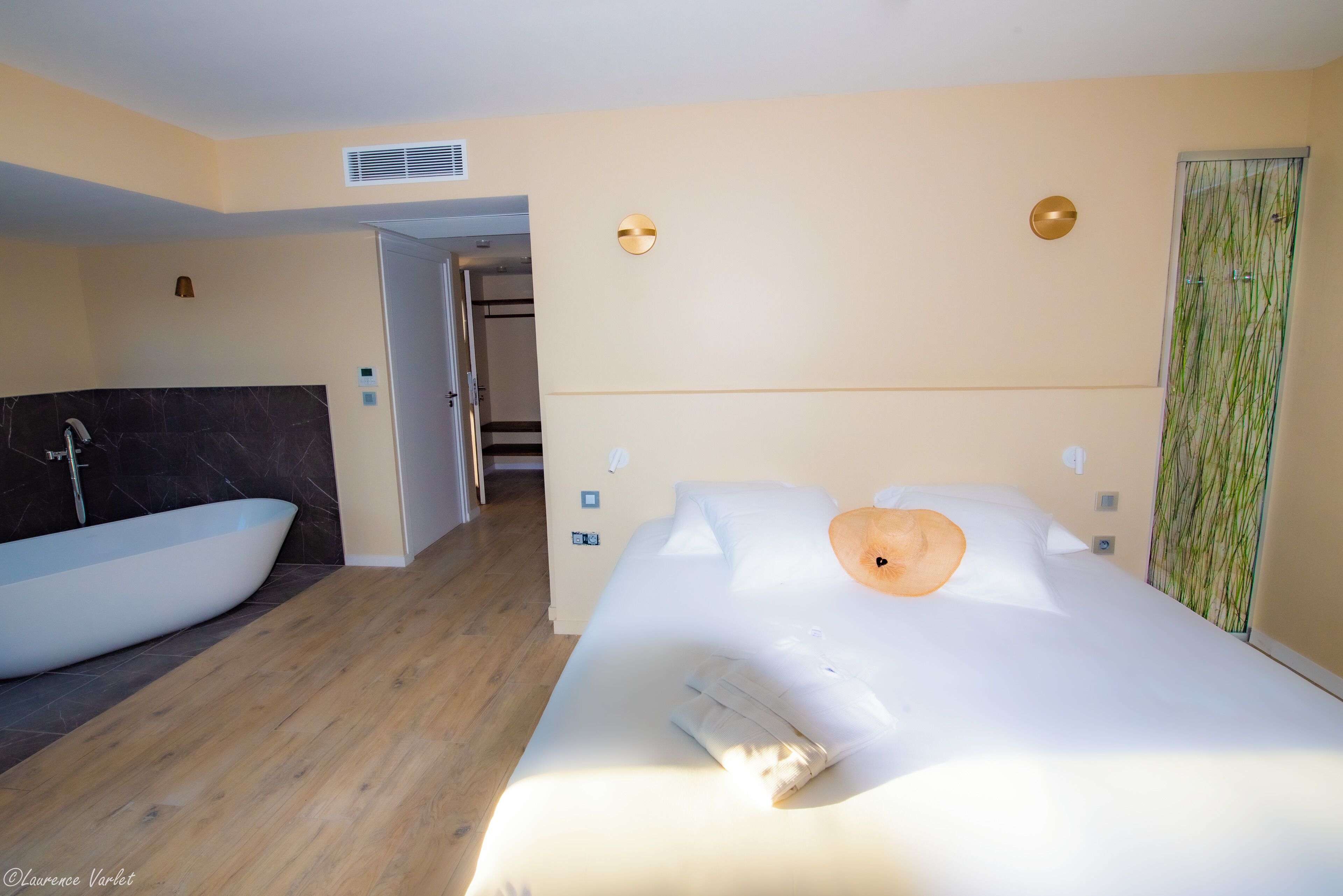 A hotel room with a large bed, a bathtub, and a walk-in closet.