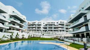 A modern hotel with a central swimming pool, multiple balconies, and a clear sky. - Luxe Appartement Orihuela-costa With Pool View (Orihuela)
