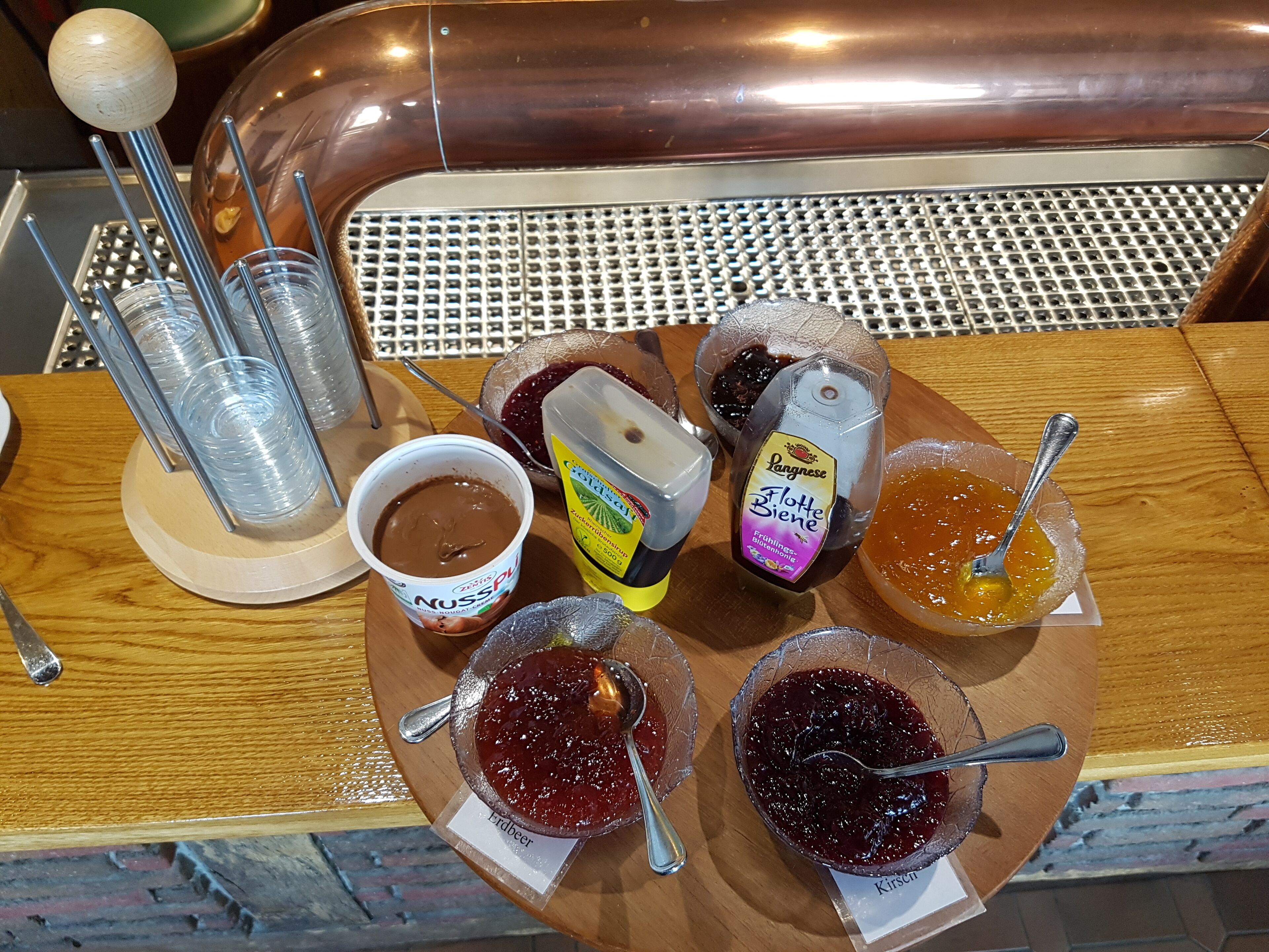 A wooden table with various food items including jars of preserves and a container of yogurt.