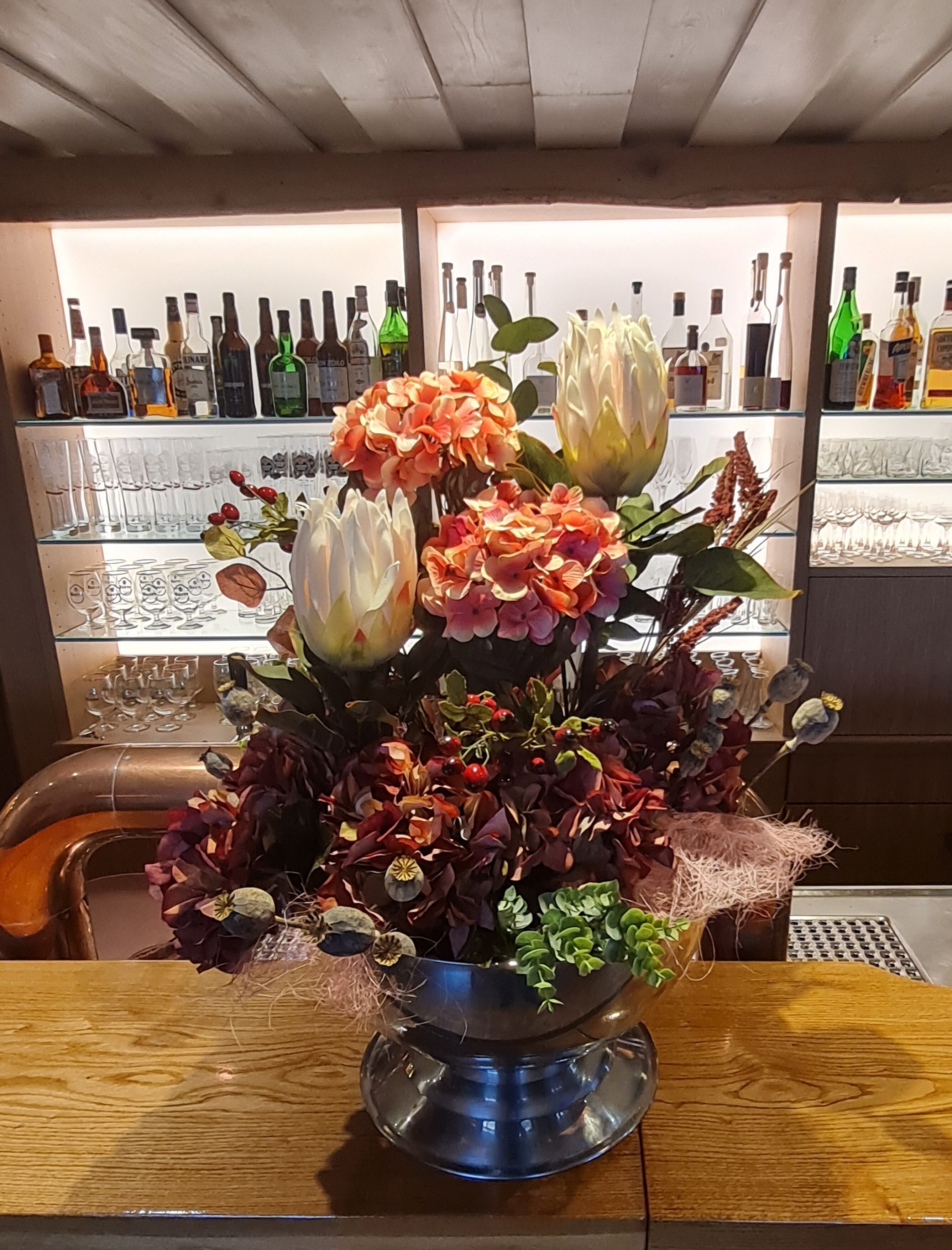Ein Tisch mit floraler Dekoration und eine Bar im Hintergrund.