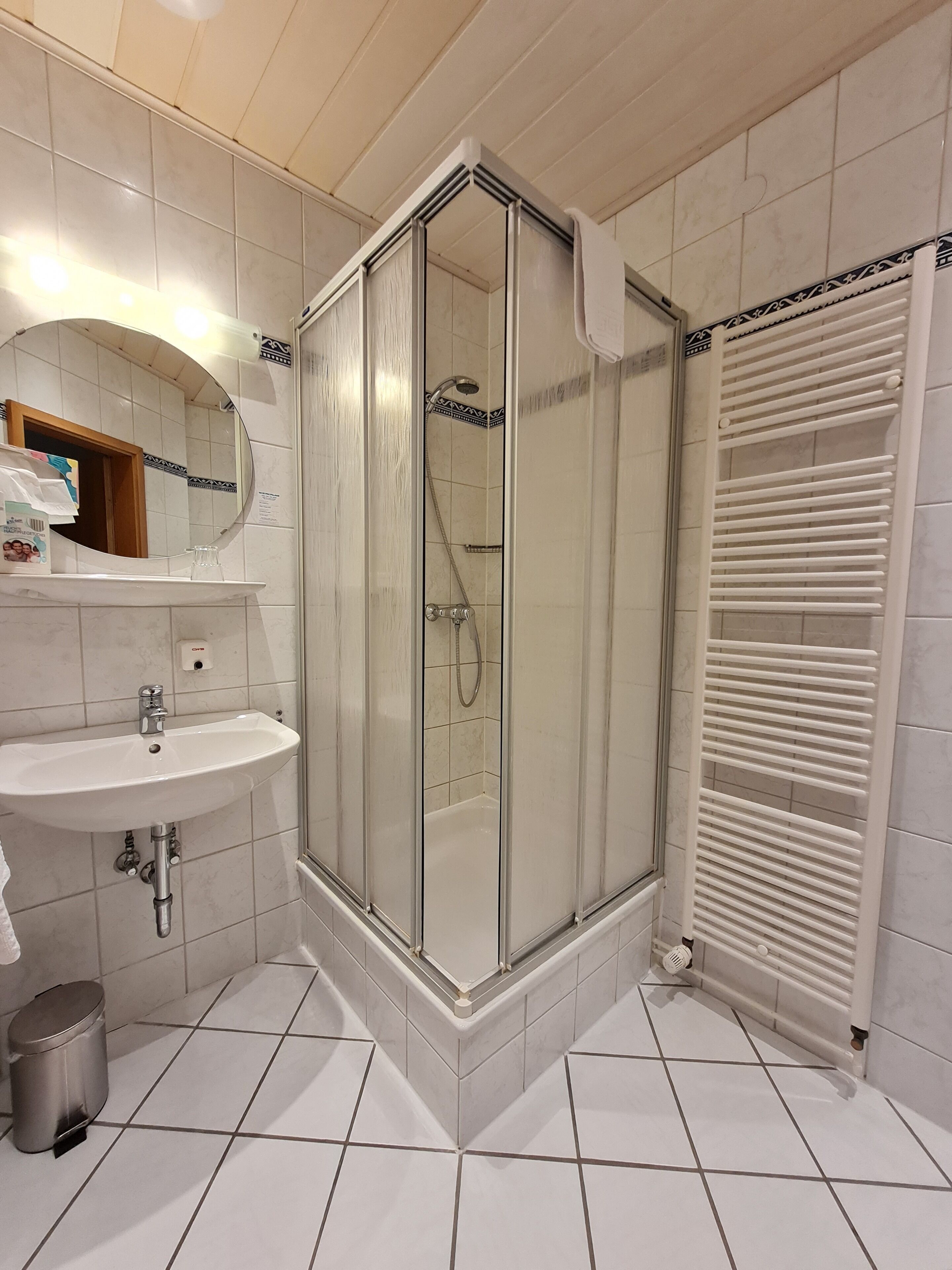 Un baño con cabina de ducha, lavamanos y toallero.