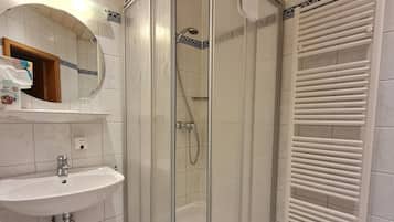 Un baño con cabina de ducha, lavamanos y toallero.