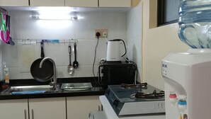 A kitchen with white cabinets, a stove, a coffee maker, and a water dispenser. - Lux Suites Kileleshwa Studio Apartments (Nairobi)