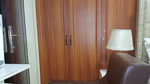 A brown leather sofa in a room with wooden cabinets and a white lamp. - Lux Suites Kileleshwa Studio Apartments (Nairobi)