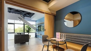 Un intérieur moderne avec un escalier, un miroir rond, un canapé et une table dont le plateau est en verre.