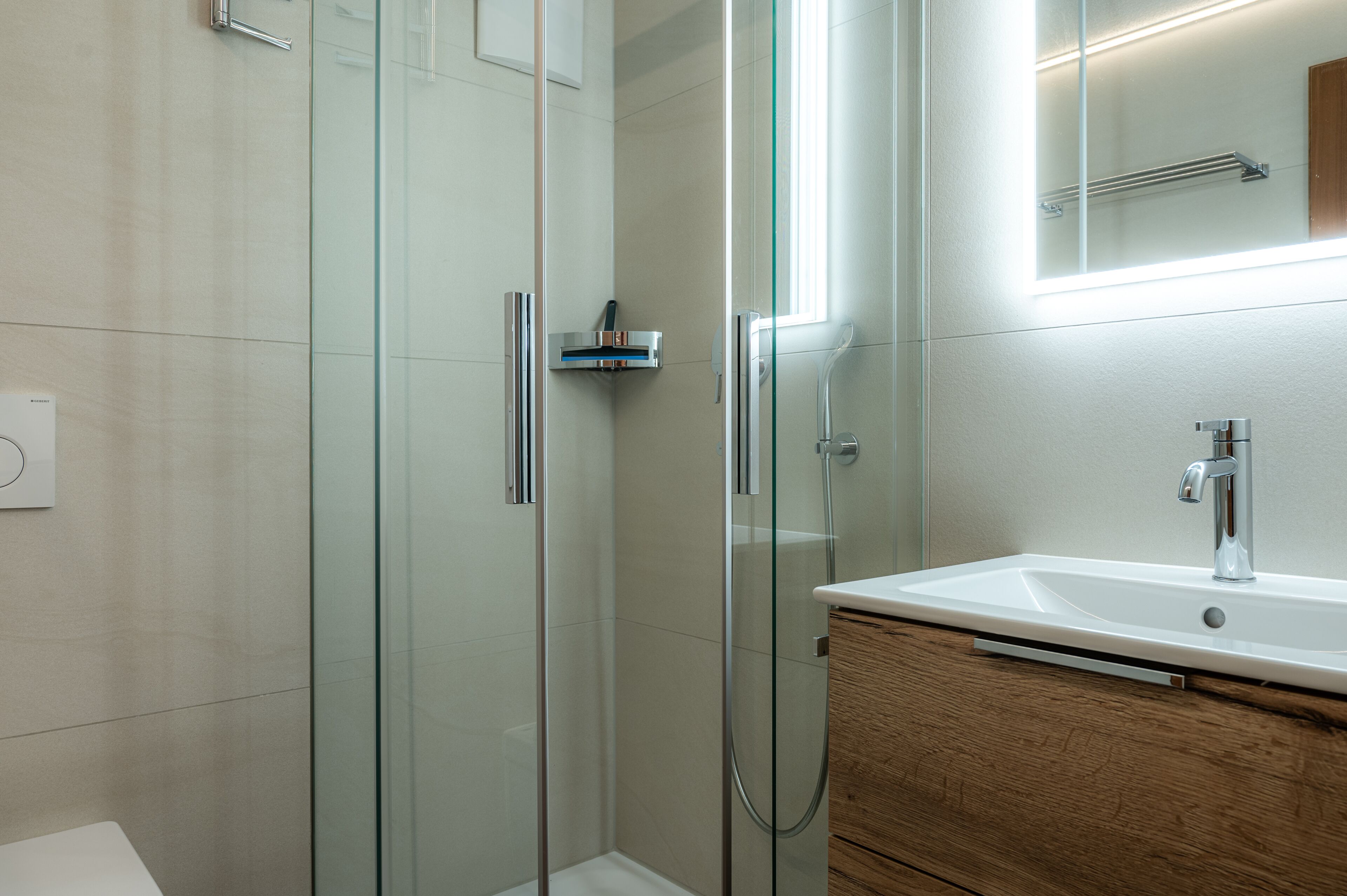 A modern bathroom with a glass shower enclosure, a wooden vanity, and a large mirror above the sink.