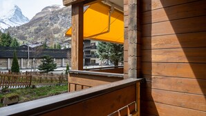 A wooden balcony with a yellow awning overlooking a mountainous landscape. - Baccara Studio  (Zermatt)