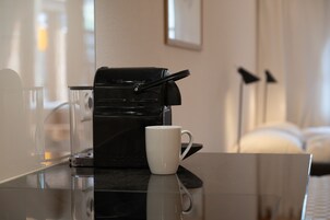 Uma cafeteira em cima de uma mesa, com uma caneca branca ao lado.