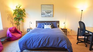 A bedroom with a bed, a desk, a chair, a plant, and a painting on the wall. - Cozy Home in Frisco/Little Elm (Little Elm)