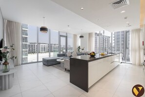 Une cuisine moderne dotée d’un îlot central, de grandes fenêtres et offrant une vue sur la ville.