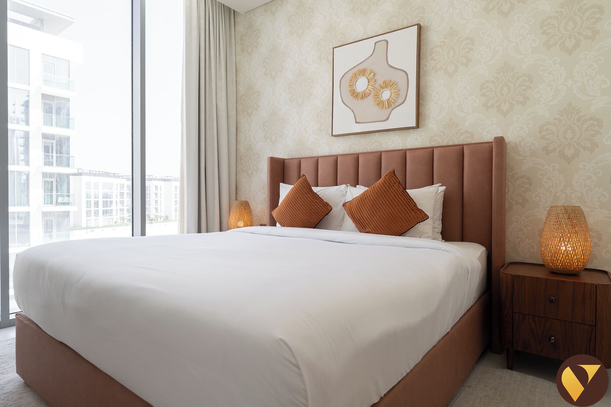 Ein Hotelzimmer mit einem großen Bett, einem Kopfteil, zwei Nachttischlampen und einem gerahmten Kunstwerk an der Wand.