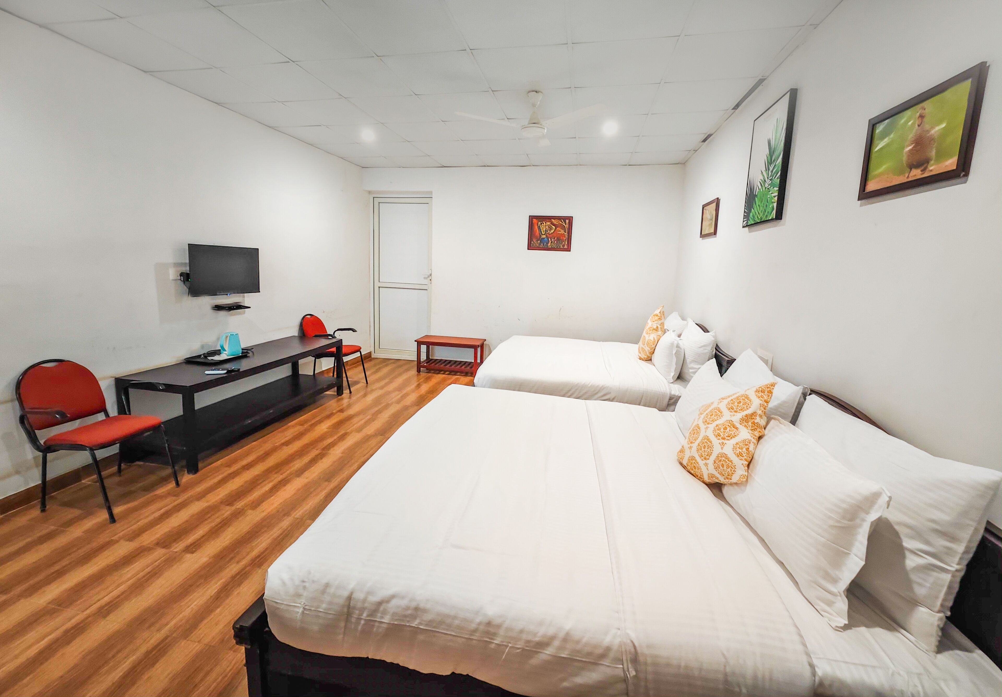 A hotel room with two beds, a desk with a chair, a television, and a door.