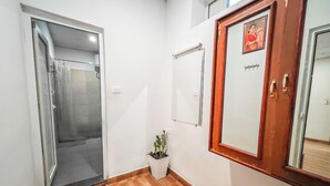 A hallway with a wooden floor, a glass door leading to a bathroom, a potted plant, and a wooden-framed door with a mirror. - Ibex Resorts, Valparai (Mistly) (Valparai)