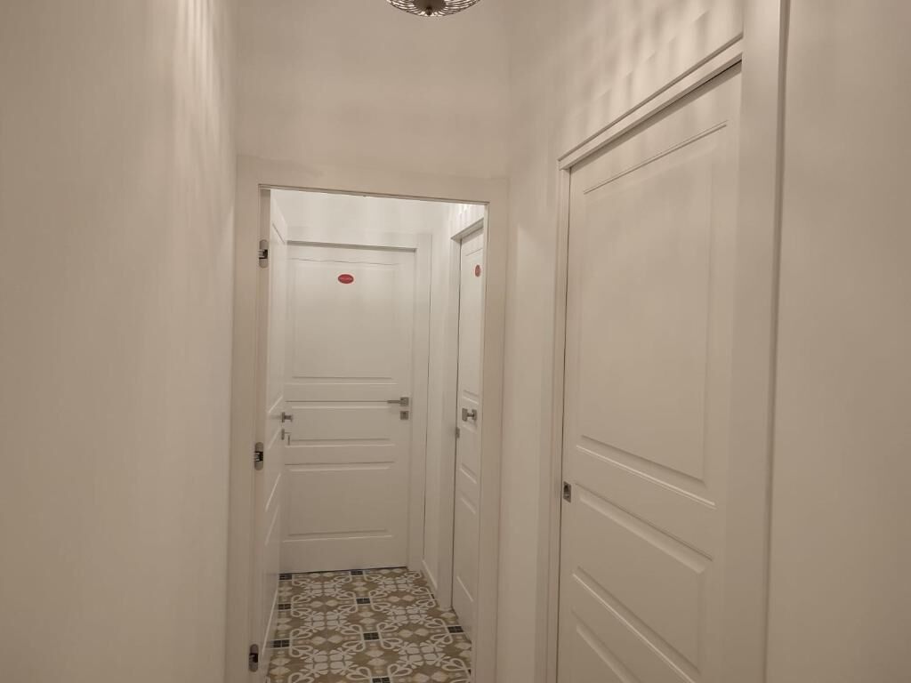 A narrow hallway with white walls and a tiled floor.