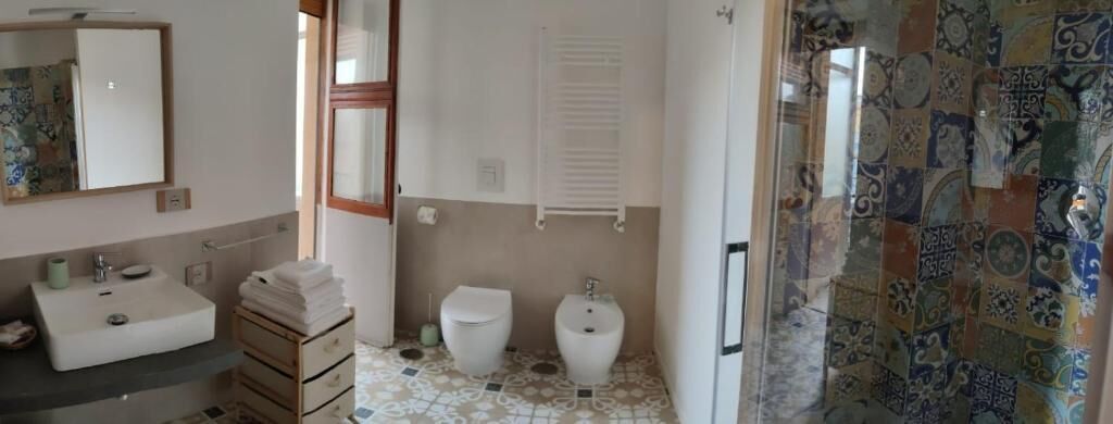 Un baño con lavamanos, dos inodoros y zona de ducha.
