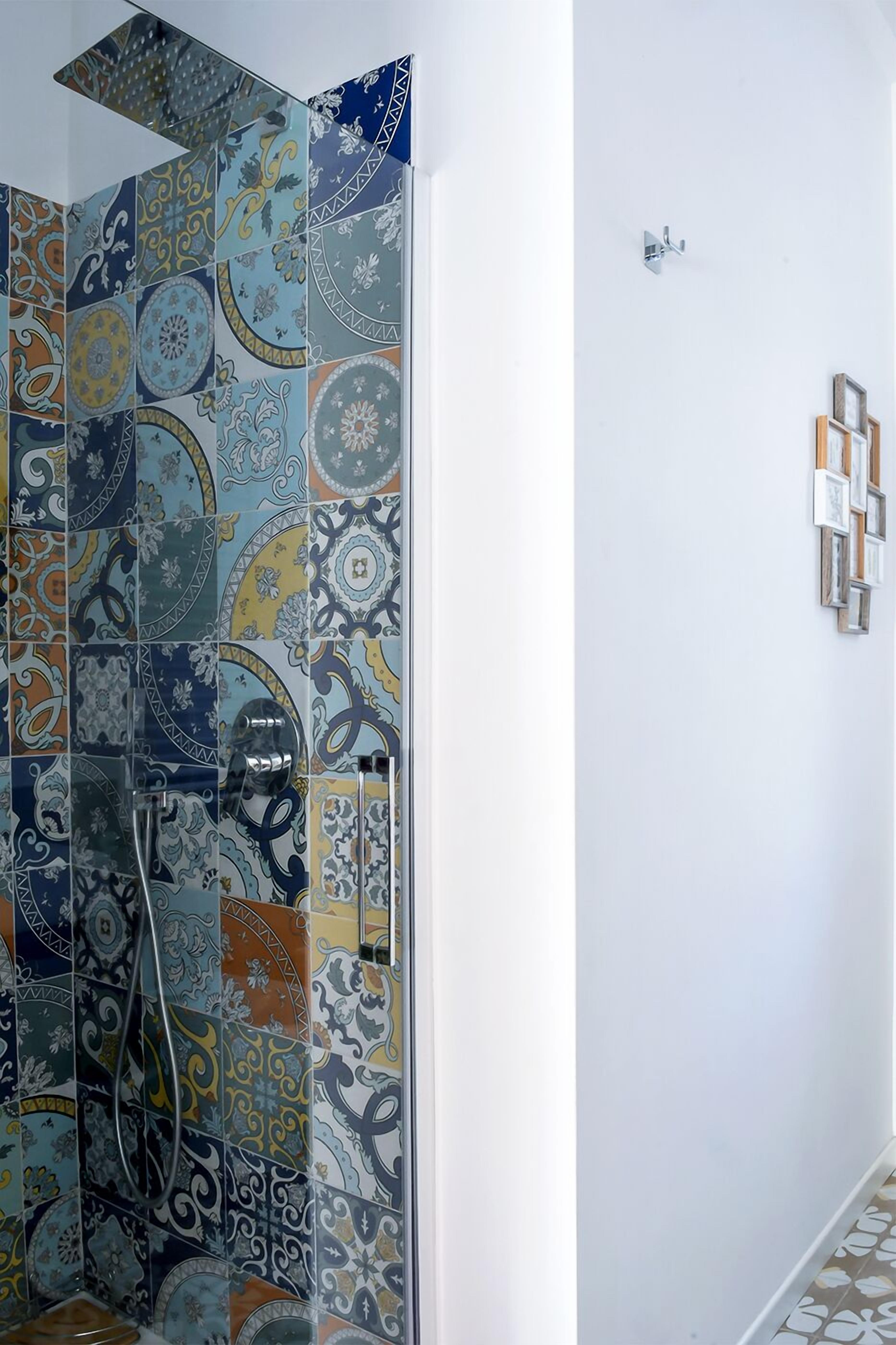 Un espace douche agrémenté de différents types de carreaux décoratifs.