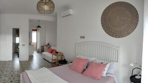 Un dormitorio con cama, mesita de noche y aire acondicionado de pared.