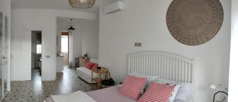 Un dormitorio con cama, mesita de noche y aire acondicionado de pared.