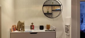 A desk with a decorative elephant, a small red box, a black speaker, and a round shelf with a plant.