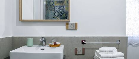 A bathroom with a white sink, a mirror, a towel rack, and a tiled backsplash.