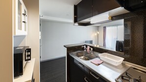 A modern kitchen with a stainless steel sink, a microwave, and dark cabinetry. - STARGAZE 602 (Sapporo)