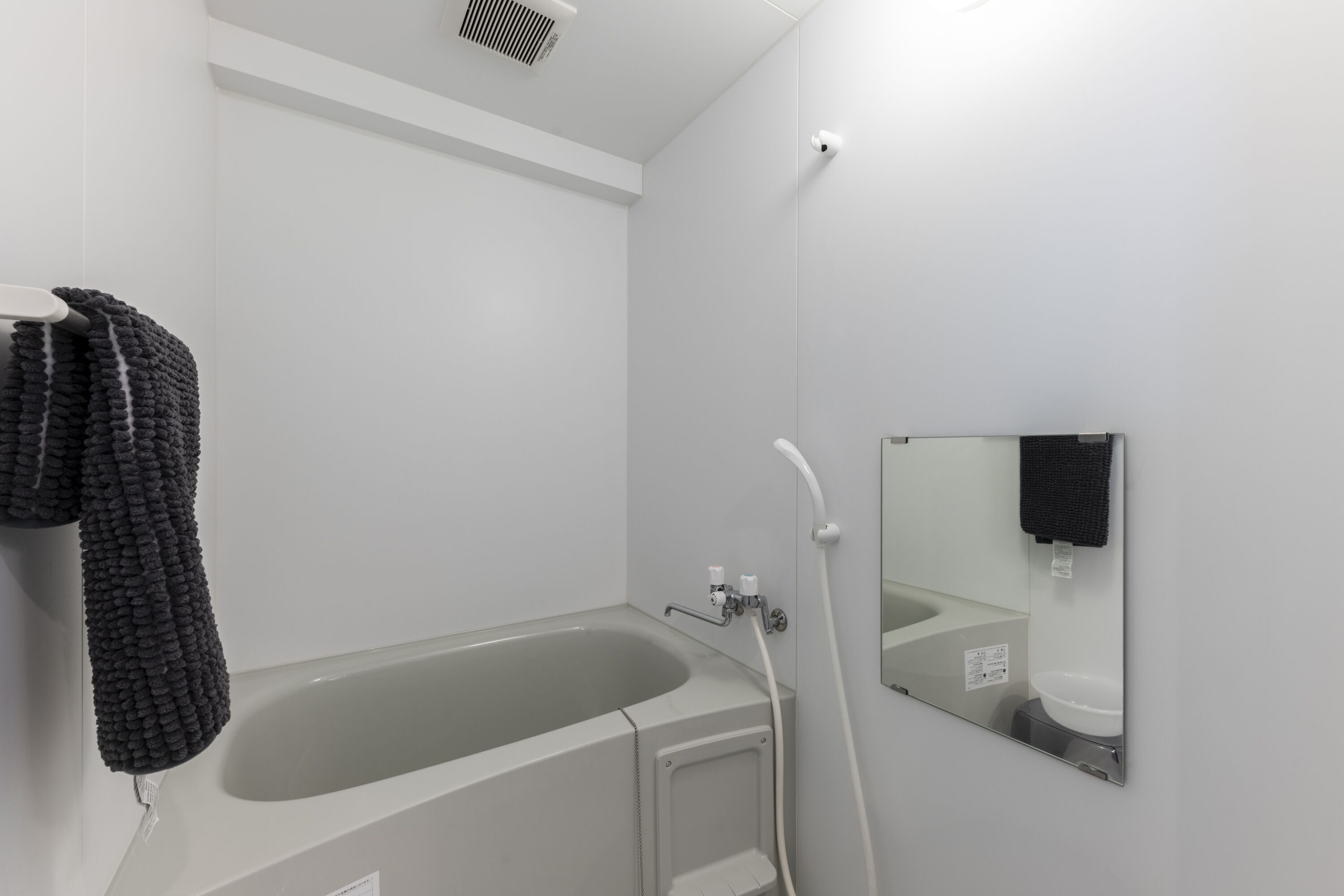 A modern bathroom with a bathtub, a shower, and a mirror.