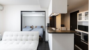 A modern hotel room with a bed, a sofa, a kitchenette, and a bathroom. - STARGAZE 602 (Sapporo)