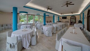 A spacious banquet hall with round tables and chairs, large windows, and ceiling fans. - Hotel Sporting (Vasto)