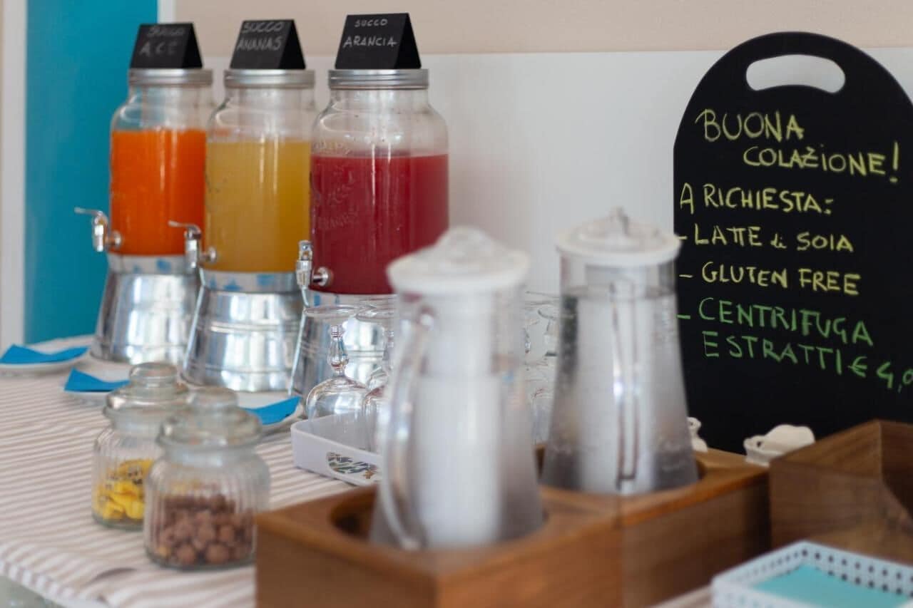 A beverage station with labeled bottles and a chalkboard menu offering options like latte, gluten-free, and espresso.